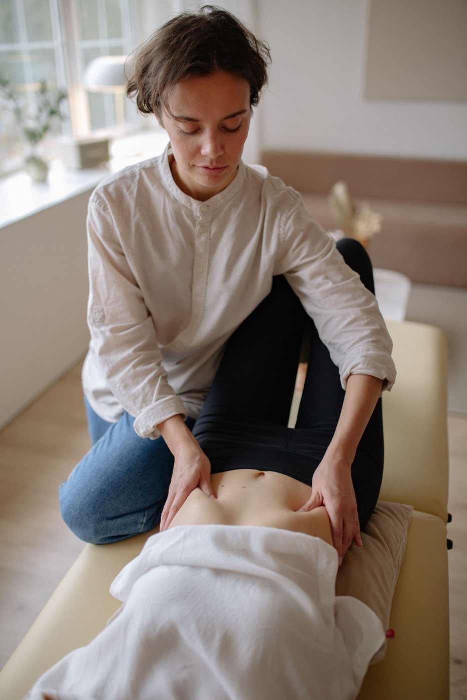 Praticienne réalisant un massage du ventre en cabine claire
